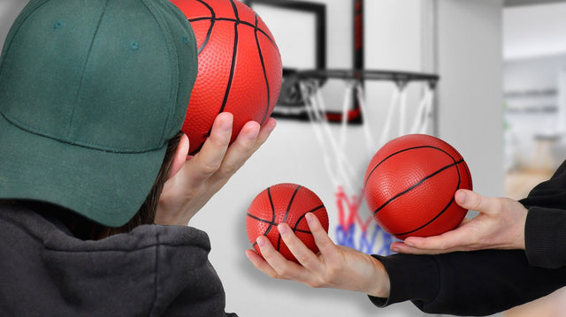 Mini-Basketballkorb an der Zimmertür, davor Hände mit einem großen und einem kleinen Indoor-Ball